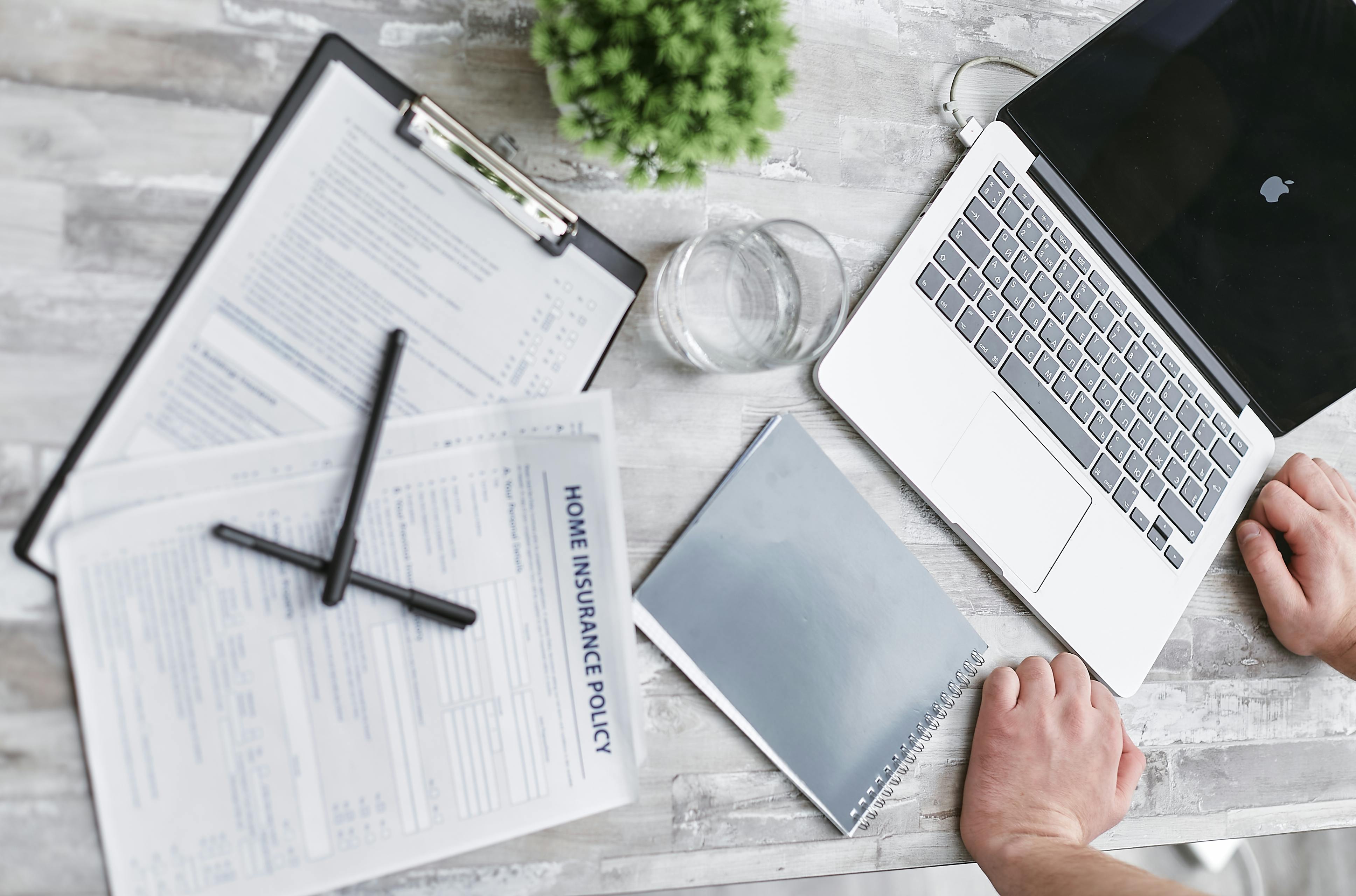 Insurance policy paperwork and laptop prepared for a refund review